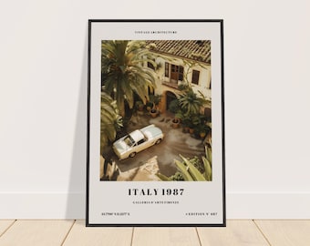 May include: A vintage poster with a black frame featuring a white car parked in a courtyard with a building in the background. The poster has the text "Vintage Architecture", "Italy 1987", "Galleria d'Arte Firenze", "43.700 N 11.257 E", and "Edition N 687".