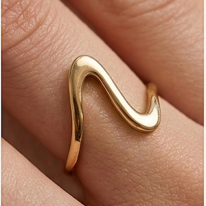 Anillo abierto de oro con diseño abstracto de ondas, joyería orgánica fluida y escultural.