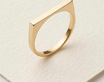 Anillo minimalista de oro con parte superior plana, diseño geométrico moderno, ideal para apilar y usar a diario.