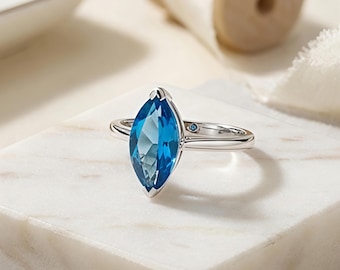 Anillo solitario de topacio azul marquesa, plata de ley, diseño minimalista.