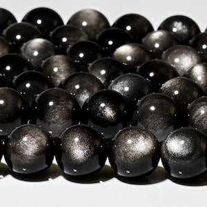 May include: A strand of black gemstone beads with a silver sheen. The beads are round and smooth, and they are arranged in a row.