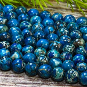 Puede incluir: Una hebra de cuentas redondas de mármol azul y blanco. Las cuentas tienen aproximadamente 8 mm de diámetro y un acabado liso y pulido.