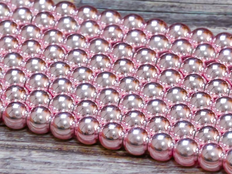 Op de afbeelding: Een close-up van een streng roze parels. De parels zijn rond en hebben een glanzende afwerking.