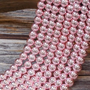 Op de afbeelding: Een streng roze glazen kralen met een hoogglans afwerking. De kralen zijn rond en uniform van grootte.