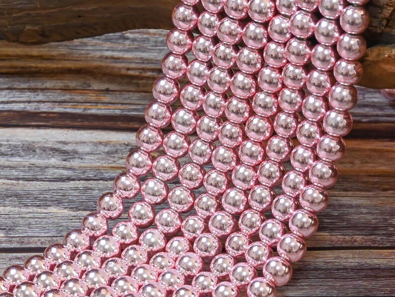 Op de afbeelding: Een streng roze glazen kralen met een hoogglans afwerking. De kralen zijn rond en uniform van grootte.