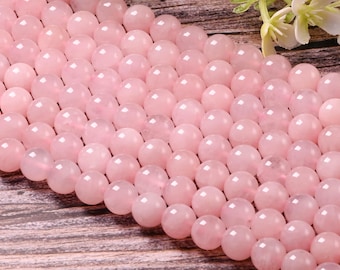 May include: A strand of pink rose quartz beads. The beads are round and smooth, and they are arranged in a close-up view.