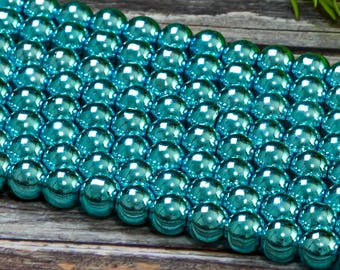 May include: A strand of turquoise blue metallic round beads. The beads are smooth and shiny, with a reflective surface.
