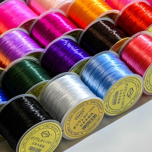 May include: A variety of spools of colorful elastic thread, each labeled with Japanese text, "ポリウレタン 100%" (Polyurethane 100%).
