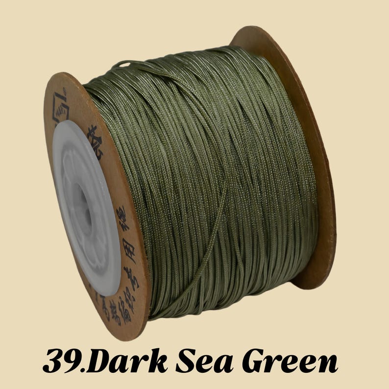 Puede incluir: Un carrete de cord&oacute;n verde mar oscuro. El cord&oacute;n est&aacute; bien enrollado en un carrete de cart&oacute;n con un n&uacute;cleo de pl&aacute;stico blanco. El texto "39. Dark Sea Green" est&aacute; en la parte inferior de la imagen.