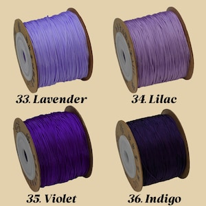 Puede incluir: Cuatro carretes de cord&oacute;n en tonos morados, lavanda e &iacute;ndigo. Cada carrete est&aacute; etiquetado con un nombre de color y un n&uacute;mero: Lavanda, Lila, Violeta e &Iacute;ndigo. El cord&oacute;n est&aacute; bien enrollado en un carrete de cart&oacute;n.