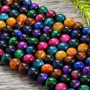 May include: A strand of colorful tiger's eye beads. The beads are round and have a smooth, polished finish. The colors include blue, green, red, orange, and yellow.