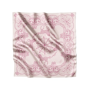 May include: A pink and white silk scarf with a delicate lace pattern and a central design of a carousel with horses. The design is in a vintage style.