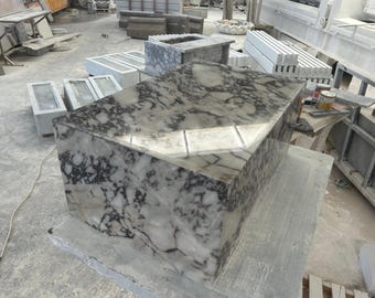 May include: A large, rectangular, white marble table top with black veining. The table top is sitting on a smaller, gray marble base.