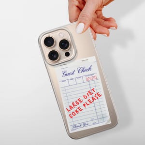 May include: A gold iPhone case with a clear back. The back of the case has a printed image of a restaurant guest check with the text "Large Diet Coke Please" written in red.
