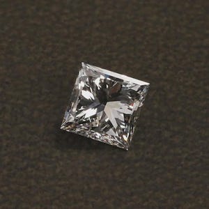 Può includere: Un diamante a taglio quadrato, con molteplici sfaccettature. La gemma è trasparente e incolore, riflettendo la luce per creare un effetto scintillante. Il diamante è posto su uno sfondo scuro.