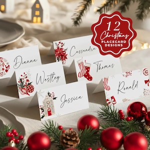 May include: White Christmas place cards with names in elegant script and festive holiday designs. Each card features unique Christmas-themed illustrations, including ornaments, stockings, and candy canes. The image includes red ornaments and pine needles.