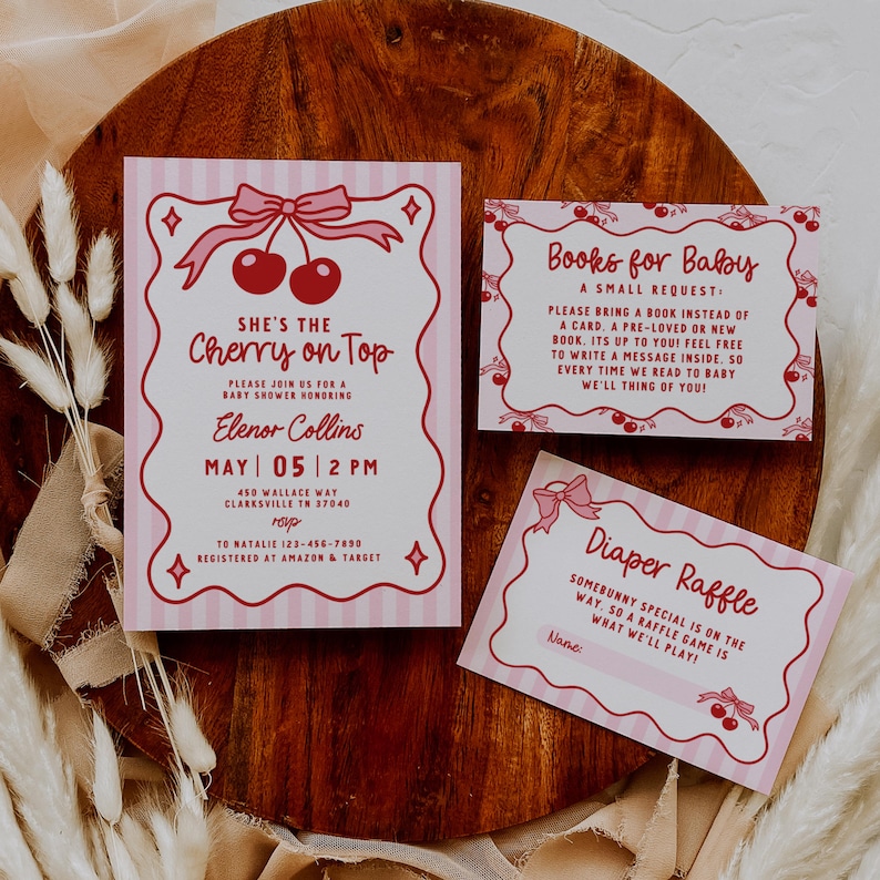May include: Pink baby shower invitations and inserts with a cherry theme. The main invitation reads "She's the Cherry on Top" and includes event details. Additional cards request books and announce a diaper raffle.