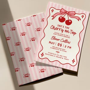 May include: Pink baby shower invitation with a cherry theme. The invitation features a cherry graphic with the text "She's the Cherry on Top" and event details. The back of the invitation has a pink and white striped pattern with cherry graphics.