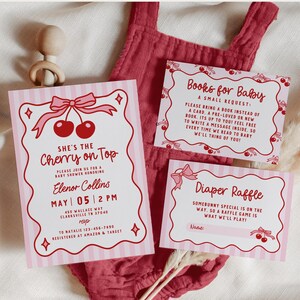 May include: Pink baby shower invitations with a cherry theme. The main invitation reads "She's the Cherry on Top" with event details. Additional cards request books and announce a diaper raffle. A wooden baby toy and pink onesie are also in the image.