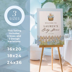 May include: A baby shower welcome sign on a wooden easel. The sign features a bunny in a basket, a picket fence, and the text "Welcome to Lauren's Baby Shower." The sign is available in 3 sizes: 16x20, 18x24, and 24x36 inches.