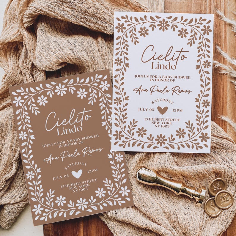 May include: Two baby shower invitations with floral borders and the text "Cielito Lindo." The invitations are in brown and white, with the details of the event. A gold wax seal and coins are on the side.