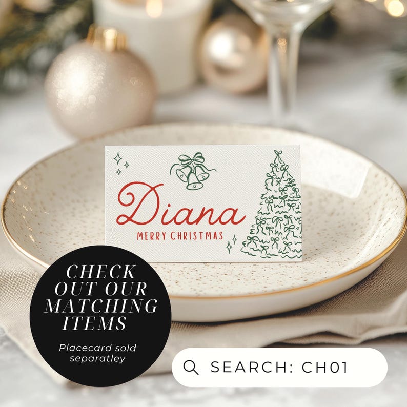 May include: A white place card with the name "Diana" in red script and "MERRY CHRISTMAS" below. The card features green bell and Christmas tree illustrations. The card is on a white plate with a gold rim.