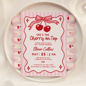 May include: A baby shower invitation with a pink and white striped design. The invitation features the text "She's the Cherry on Top" with a cherry illustration. The invitation also includes the date, time, and location of the event.