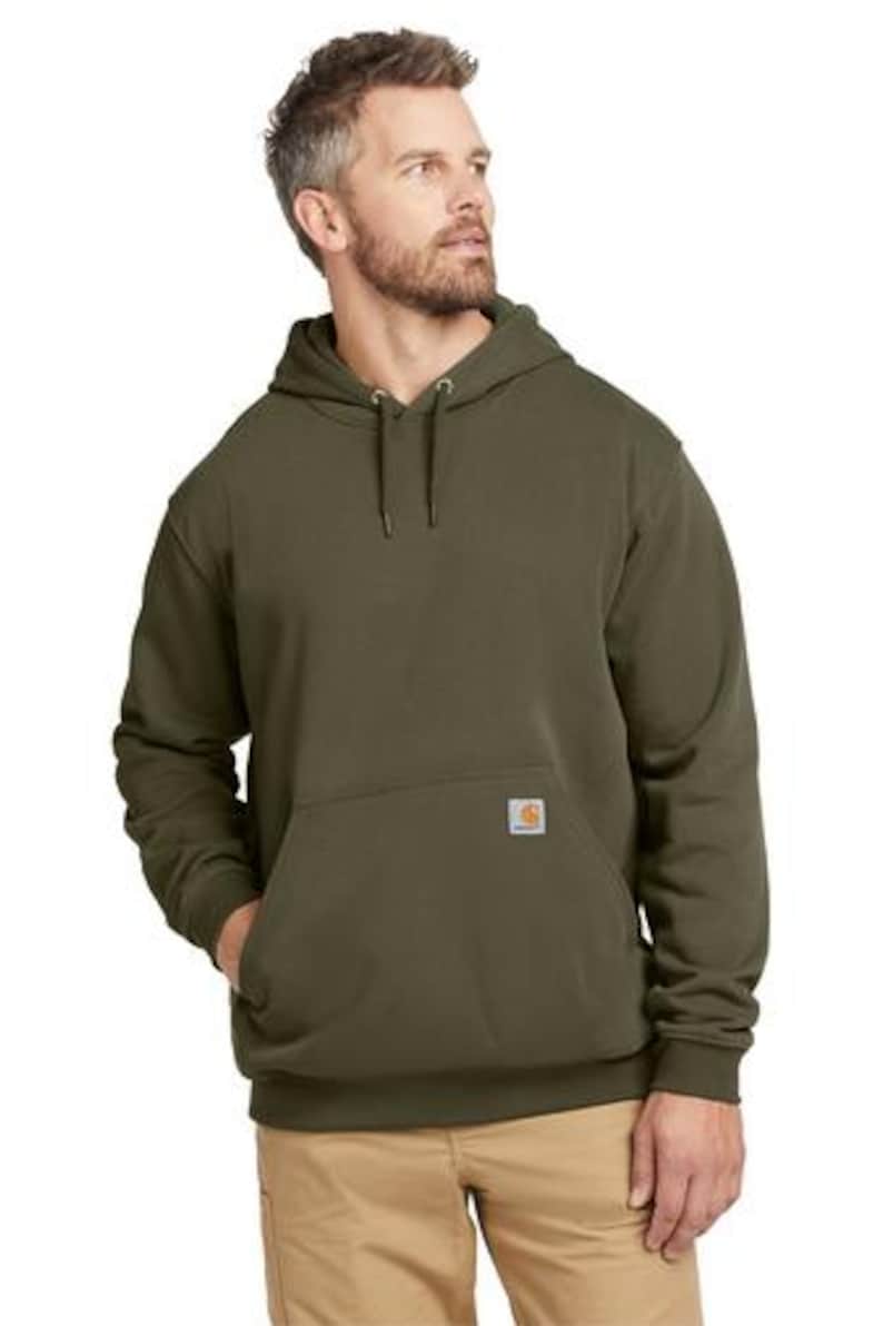 Puede incluir: Sudadera con capucha verde oliva con bolsillo de canguro y un peque&ntilde;o parche cuadrado con el logotipo. La sudadera tiene una capucha con cord&oacute;n y pu&ntilde;os y dobladillo de canal&eacute;. El modelo lleva pantalones color caqui.