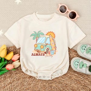 May include: A white baby onesie with a graphic of a blue van with a surfboard and palm trees. The text "ALWAYS Salty" is printed below the van.
