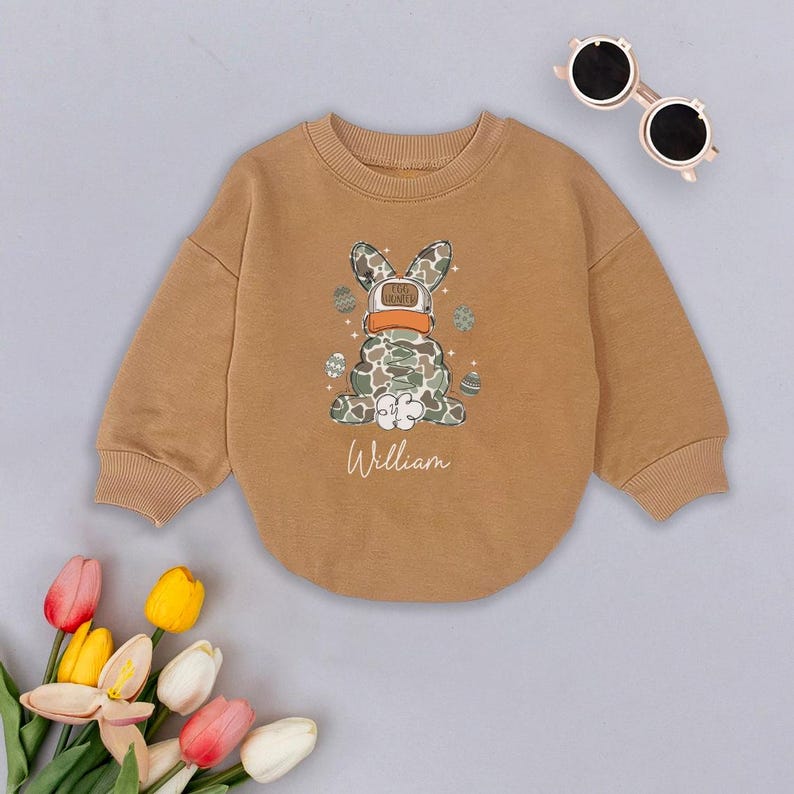 May include: A brown sweatshirt with a camouflage bunny wearing a hat that says "I'm bunny" and the name "William" printed on the front.