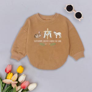 May include: A brown sweatshirt with a graphic of a bunny, a cross, a lamb, and the text "Silly bunny, Easter is about the lamb. John 1:29".