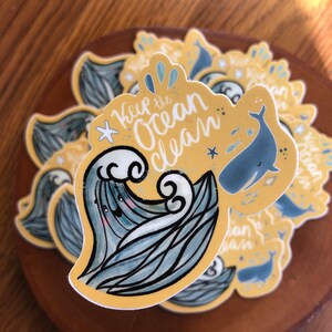 May include: A yellow sticker with a blue whale and waves. The sticker says "Keep the ocean clean".