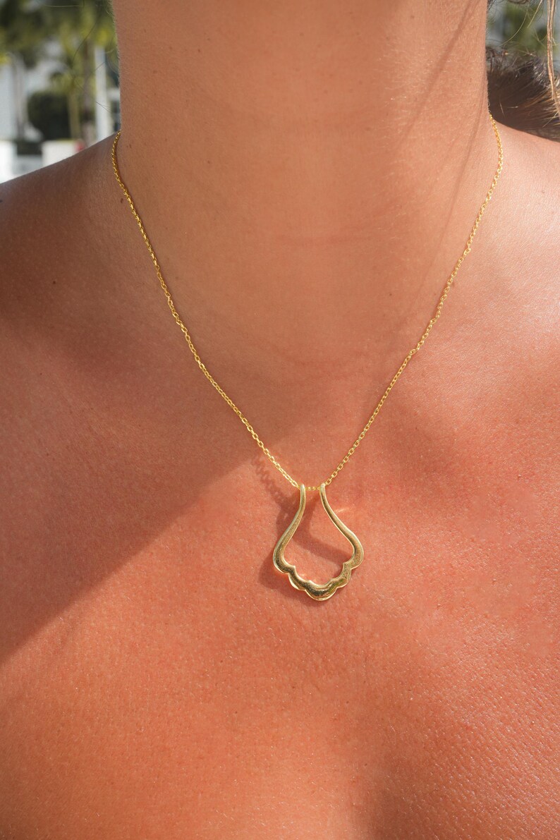 May include: A gold chain necklace with a delicate, open-work pendant shaped like a stylized flower.