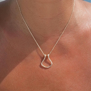 May include: A gold chain necklace with a simple, teardrop-shaped pendant.