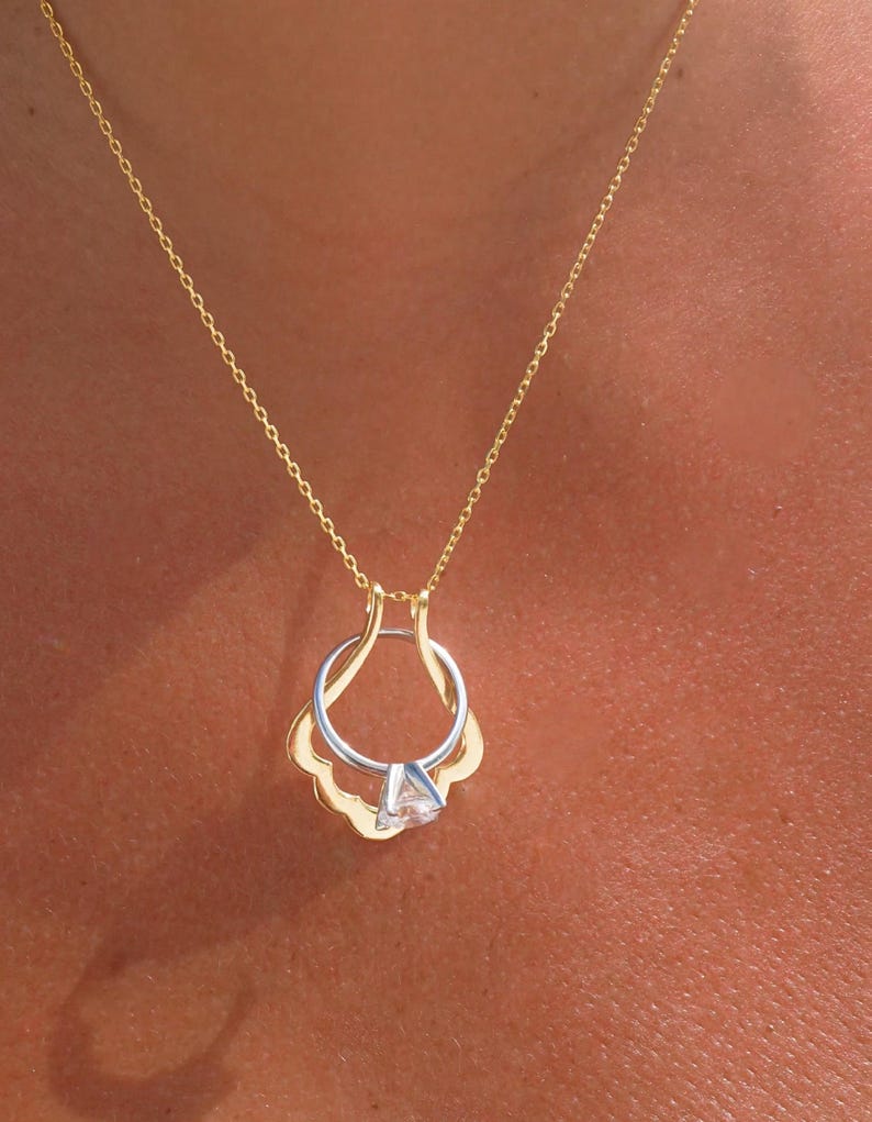 May include: A gold chain necklace with a ring holder pendant. The ring holder is shaped like a shell and has a small diamond ring inside.