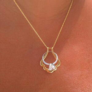 May include: A gold chain necklace with a pendant featuring a ring with a clear gemstone set in a gold and silver setting.