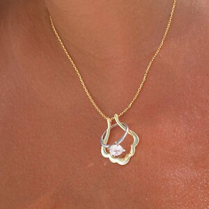 May include: A gold chain necklace with a pendant featuring a clear crystal stone set in a gold and silver ring design.