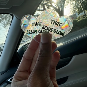 Puede incluir: Un llavero en forma de corazón iridiscente con el texto "That Jesus Glow" en él.