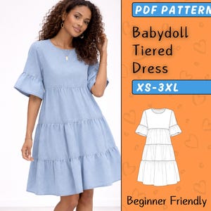 Könnte beinhalten: Ein hellblaues Babydoll-Stufenkleid mit kurzen, ausgestellten Ärmeln. Das Kleid hat einen runden Ausschnitt und einen Stufenrock. Das Bild enthält auch den Text "PDF Pattern", "Baby doll Tiered Dress", "XS-3XL" und "Beginner Friendly".