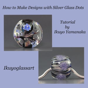 May include: Two glass beads with silver and black swirls and blue flowers. The beads are on a silver chain. The text "Tutorial by Ikuyo Yamanaka" and "Ikuyoglassart" are visible in the image.