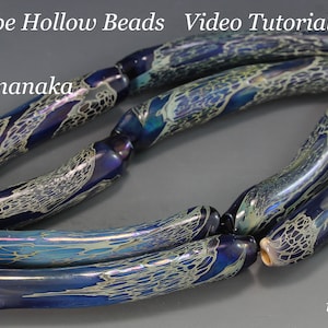 Pode incluir: Várias contas de vidro longas e ocas em tons de azul e branco são exibidas. As contas têm uma forma curva, semelhante a um tubo, com padrões intrincados em forma de teia. O texto na imagem diz "Long Tube Hollow Beads Video Tutorial by Ikuyo Yamanaka" e "ikuyoglassart".