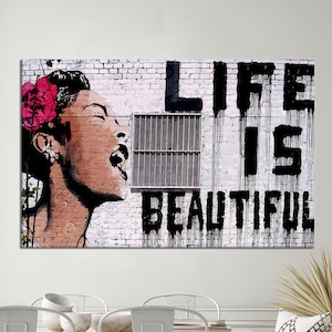 Könnte beinhalten: Schwarz-weißes Graffiti-Kunstwerk an einer Backsteinmauer mit den Worten "Das Leben ist schön" und einem Porträt einer Frau mit einer rosa Blume im Haar.
