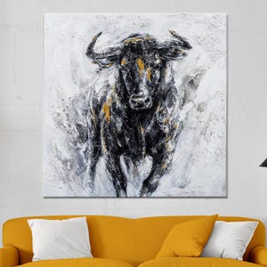 May include: A black and gold bull painting with a white background. The bull is charging forward with its horns raised. The painting is done in a textured style, giving it a three-dimensional look.
