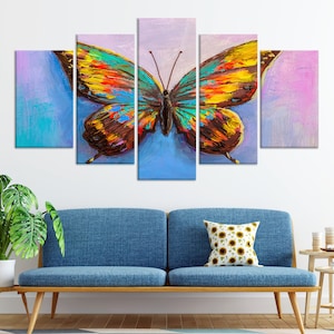 May include: A five-panel canvas art piece featuring a vibrant butterfly painting. The butterfly has colorful wings with shades of yellow, orange, blue, and brown. The background has blue and purple hues, creating an abstract effect.