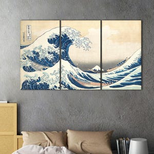 May include: A triptych canvas print of Hokusai's "The Great Wave off Kanagawa." The artwork depicts a large ocean wave with boats and Mount Fuji in the background. The wave is a deep blue, contrasting with the lighter sky and the boats.