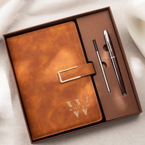 May include: A brown leather-look notebook with a gold-toned rectangular clasp and the engraved name WILLAM, presented in a gift box alongside a matching dark brown ballpoint pen and a single silver-toned ink refill cartridge.