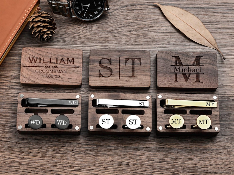 May include: Wooden box set with three compartments, each containing a tie clip and cufflinks. The boxes are engraved with the names "William", "ST", and "Michael".