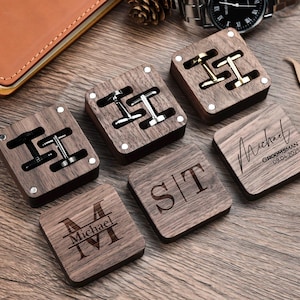 May include: Five wooden boxes with engraved names and dates. Two boxes contain cufflinks, and three boxes have engraved initials. The boxes are made of dark wood with a natural finish.