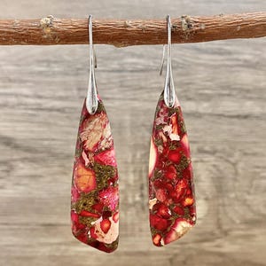 Könnte beinhalten: Ein Paar Hängeohrringe mit roten, weißen und goldenen Jaspis-Steinen. Die Ohrringe haben silberne Haken.