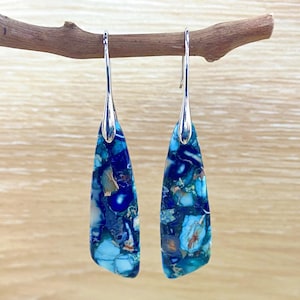 May include: A pair of silver dangle earrings with blue and green marbled stone drops. The stones have a unique, speckled pattern.
